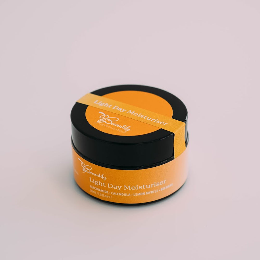 Orange and black jar of light day moisturizer on a light gray background