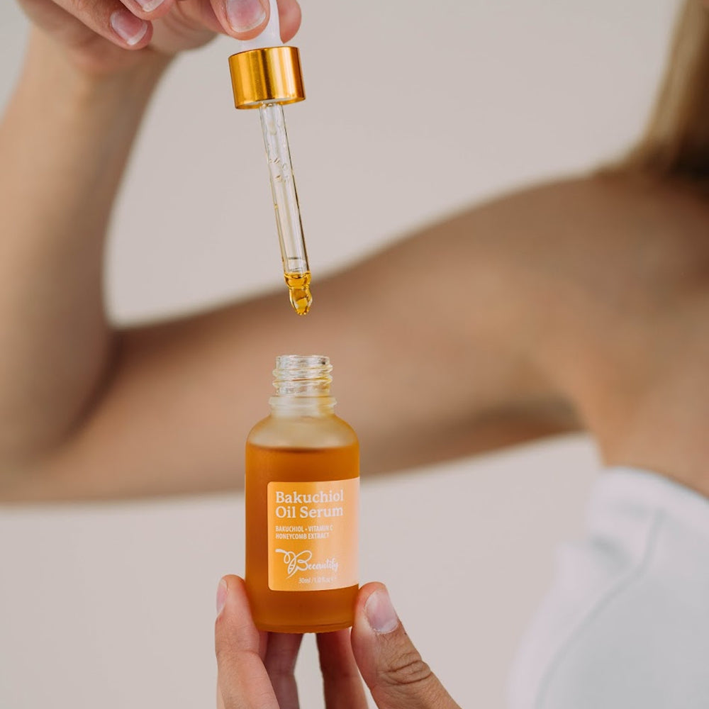 Person holding a bottle of Bakuchiol Oil Serum with a dropper.
