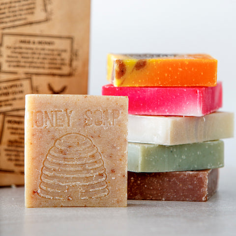 Stack of colorful soap bars with a 'Honey Soap' bar in front, on a light background.