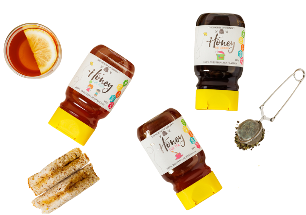 Honey bottles, a teacup with lemon, toast, and a tea infuser on a white background