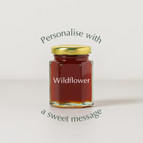 Jar of wildflower honey with a gold lid on a light background, featuring text about personalization.